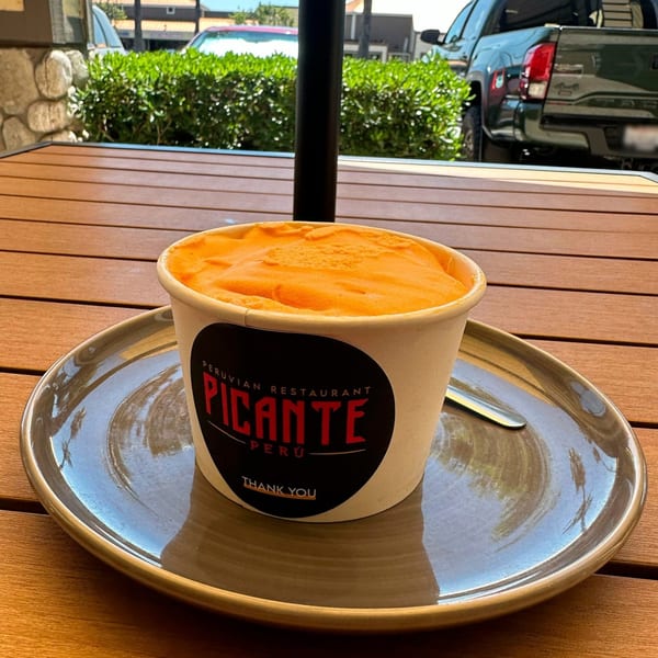 A cup of orange Peruvian ice cream from Picante restaurant on a wooden table.